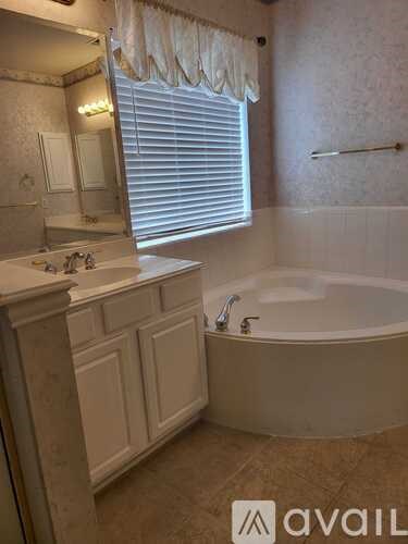A bathroom with a tub, sink, and mirror.