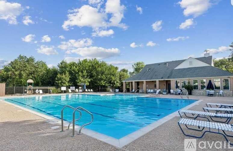 A large swimming pool with a diving board and sun loungers in front of a house.