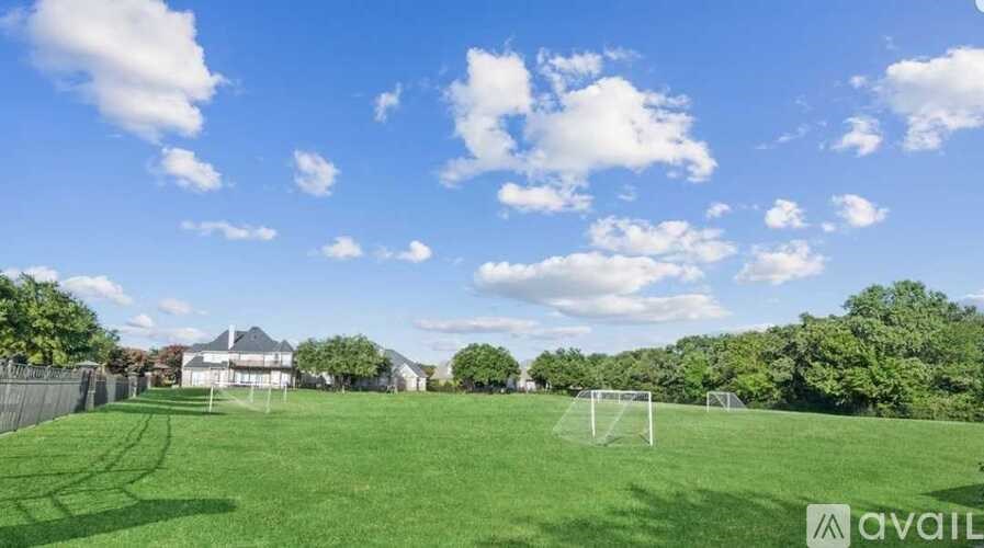 A soccer field with a goal post in the middle and a house in the background.
