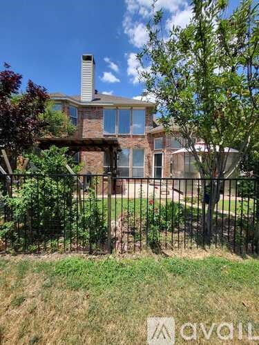 A house with a black fence and a tree in front.