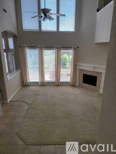 A living room with a fireplace and a fan on the ceiling.
