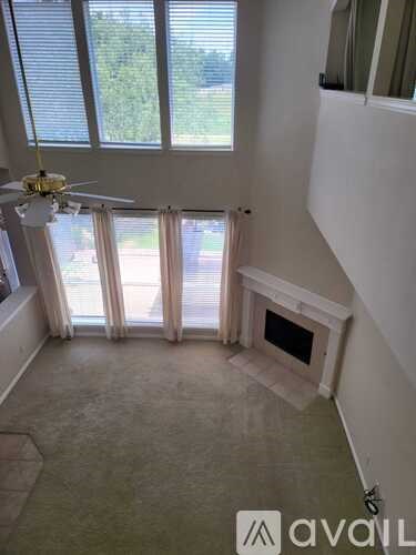 A living room with a fireplace and a ceiling fan.