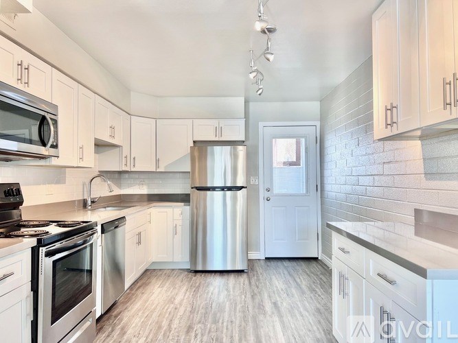 A kitchen with white cabinets and a stainless steel refrigerator.