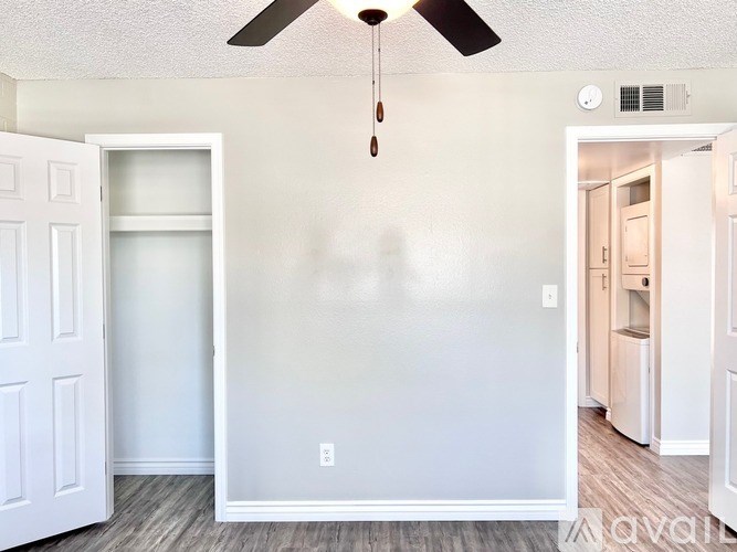 A room with a ceiling fan and a door on the left.