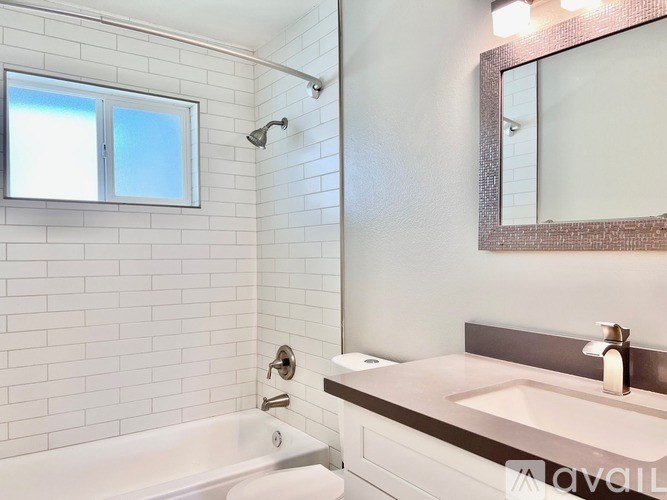 A white bathroom with a tub, sink, mirror, and window.
