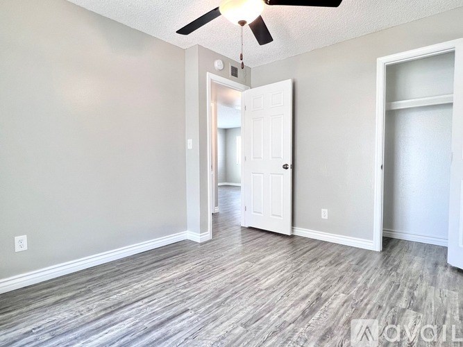 A room with a ceiling fan and wood flooring.