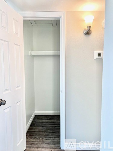 A white door is open to a hallway with a light on the wall.