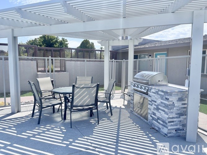 A patio with a table and chairs and a grill.
