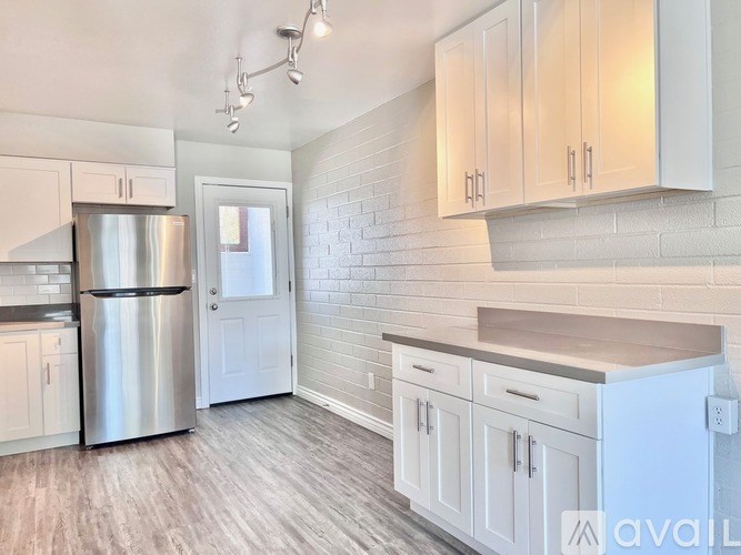 A kitchen with white cabinets and a stainless steel refrigerator.