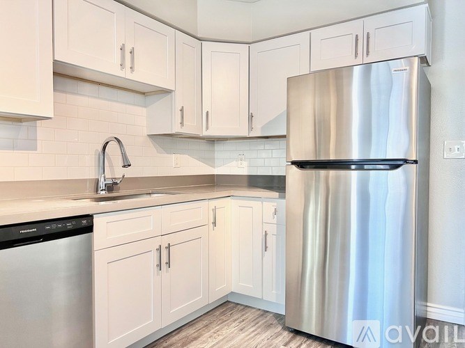 A kitchen with white cabinets and a stainless steel refrigerator.