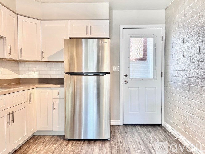 A kitchen with a stainless steel refrigerator and white cabinets.
