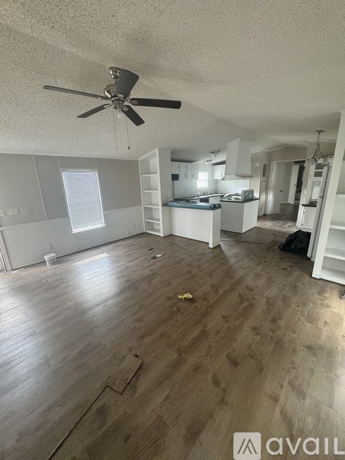 A room with a ceiling fan and wooden flooring.