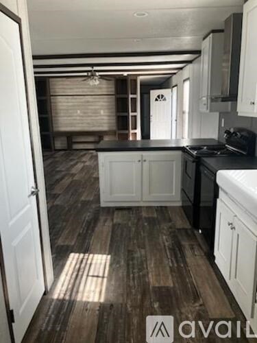 A kitchen with white cabinets and a wooden floor.