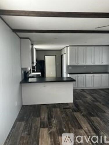 A kitchen with a black countertop and wooden flooring.