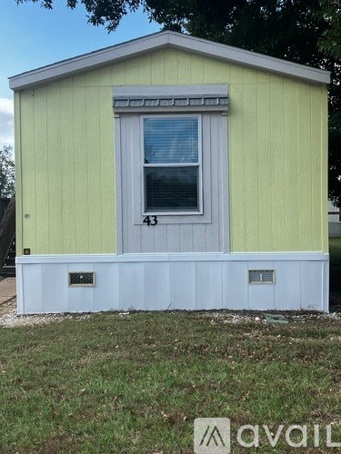 A small house with a yellow and white exterior and a blue door.