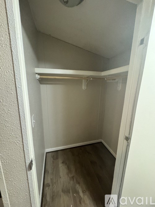 A small, empty room with a wooden floor and white walls.