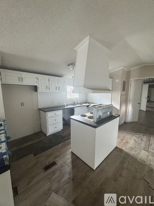 A kitchen with white cabinets and a white island with a black countertop.