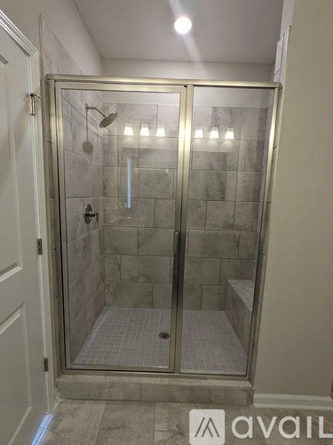 A glass shower stall with a glass door and a glass shower head.