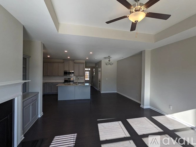 A spacious living room with a fireplace and a kitchen in the background.