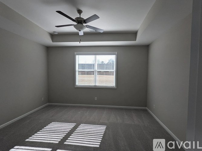 A room with a ceiling fan and a window with blinds.