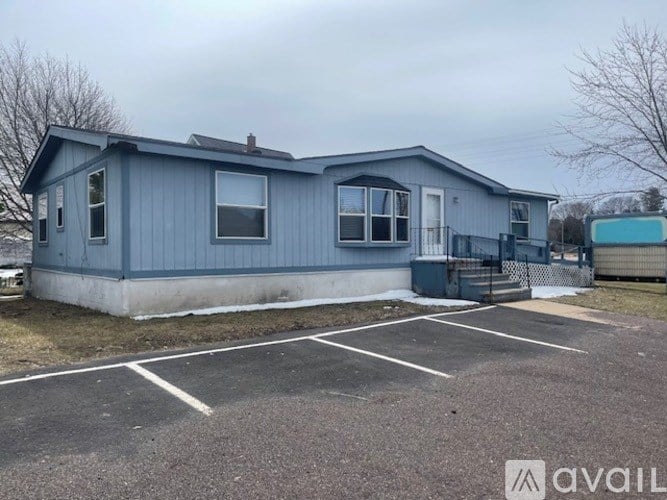 A blue house with a parking lot in front.