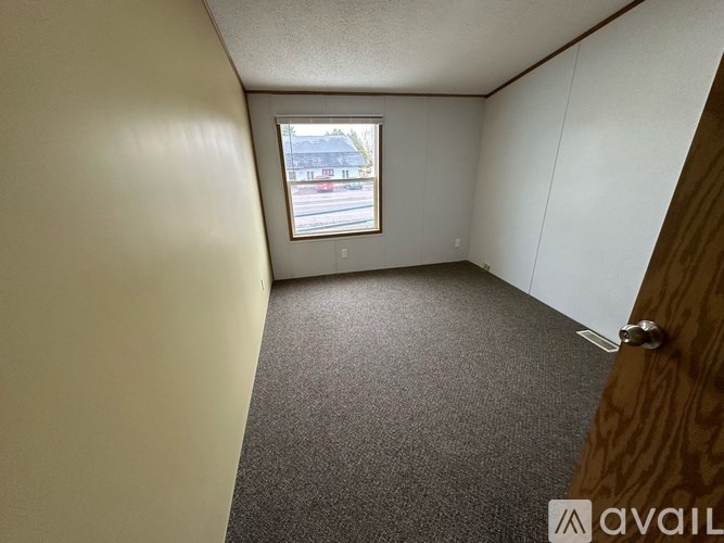 A room with a window and a carpeted floor.