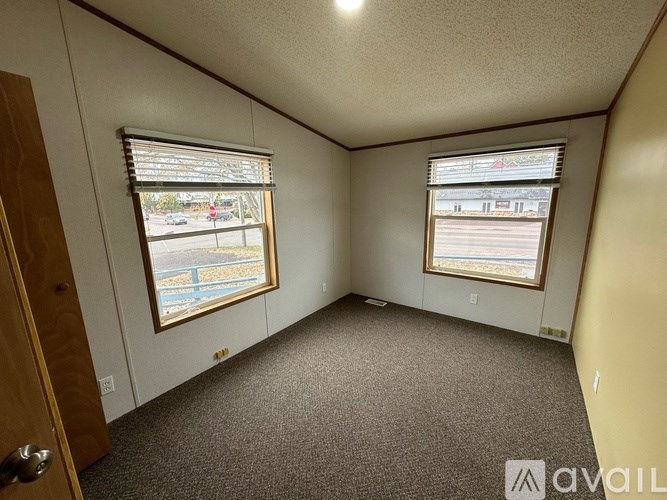 A room with a carpeted floor, a window with blinds, and a door.