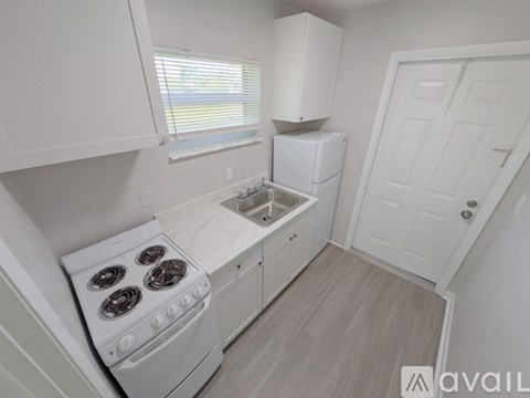 A small kitchen with a white stove and cabinets.