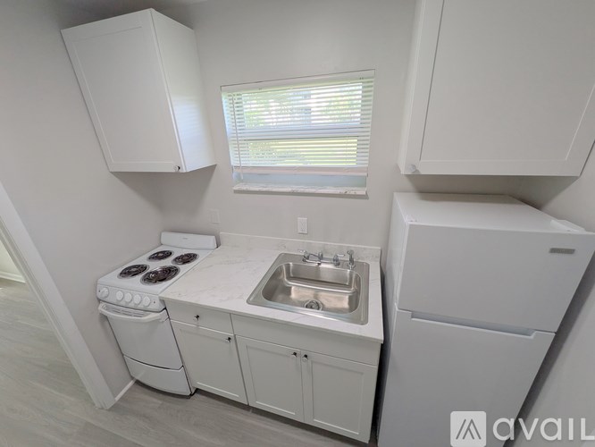 A small kitchen with a white stove, sink, and cabinets.