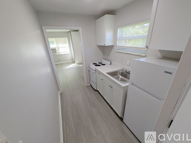 A small, white kitchen with a sink and stove.