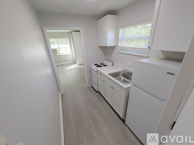 A small, white kitchen with a sink and stove.