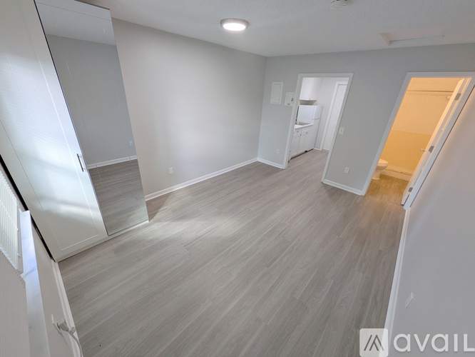 A spacious room with light grey walls and a wooden floor.
