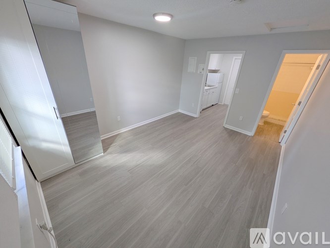 A spacious room with light grey walls and a wooden floor.
