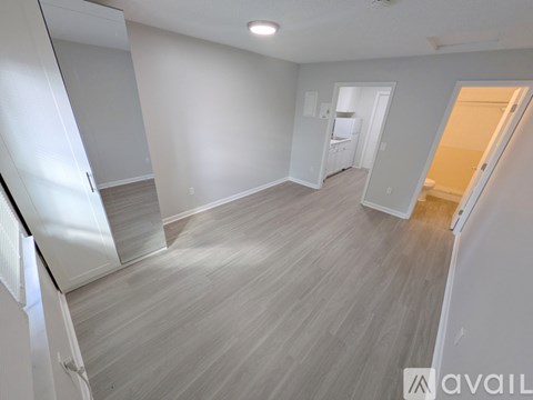 A spacious room with light grey walls and a wooden floor.