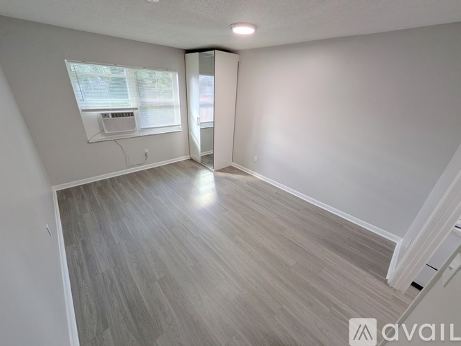 A room with a grey floor and a white wall with a window.