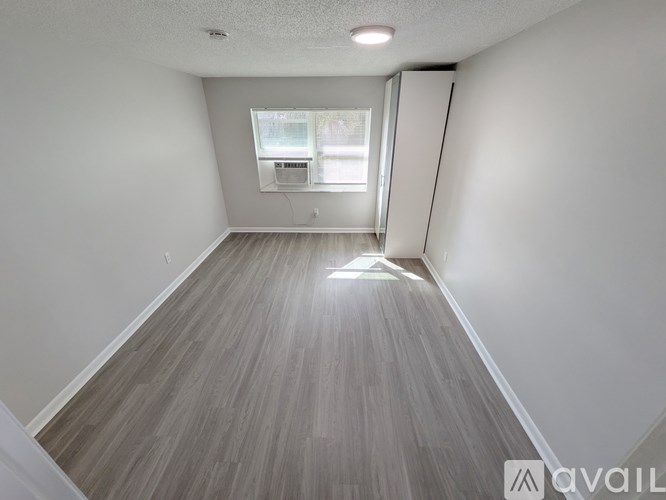 A room with a window and a wooden floor.