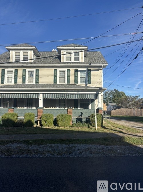 A two-story house with a porch and green shutters.