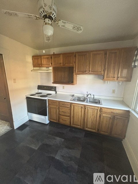 A kitchen with wooden cabinets and a black floor.