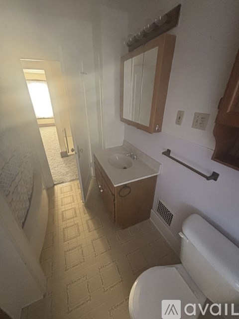 A bathroom with a toilet, sink, and mirror.