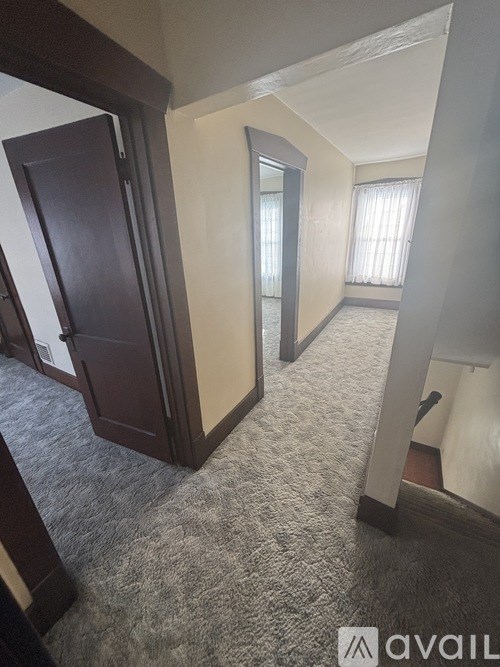 A hallway with a carpeted floor and a door on the left.