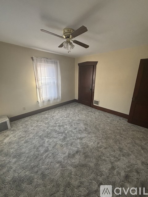 A room with a ceiling fan and a carpeted floor.