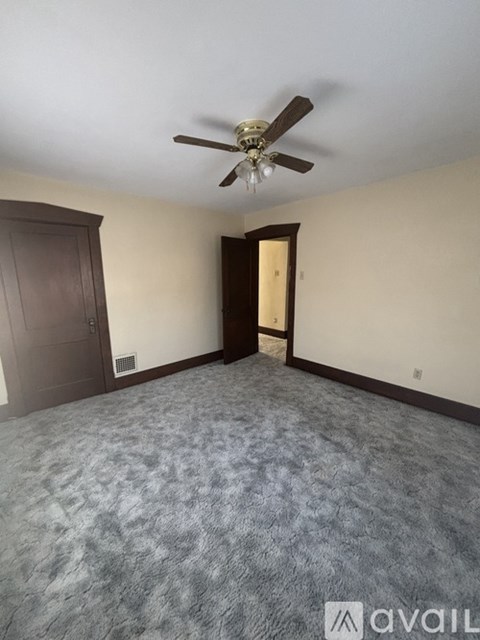 A room with a ceiling fan and carpeted floor.