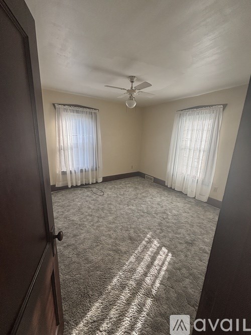 A room with a carpeted floor and a ceiling fan.