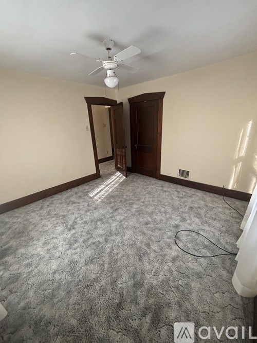 A room with a carpeted floor and a ceiling fan.