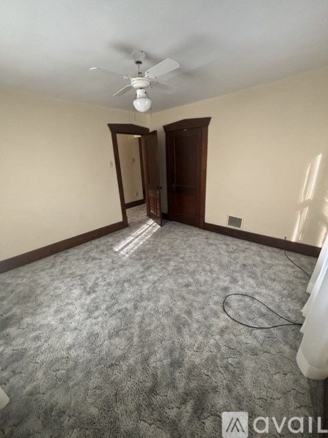 A room with a carpeted floor and a ceiling fan.