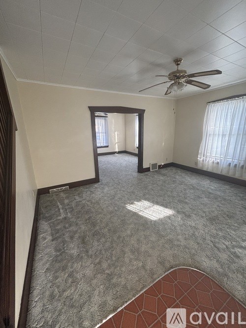 A room with a ceiling fan and carpeted floor.