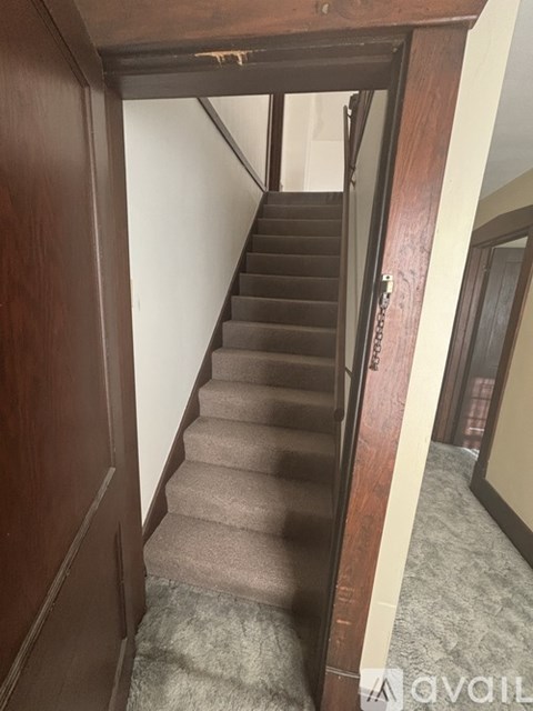 A staircase with a carpeted runner and wooden handrail.