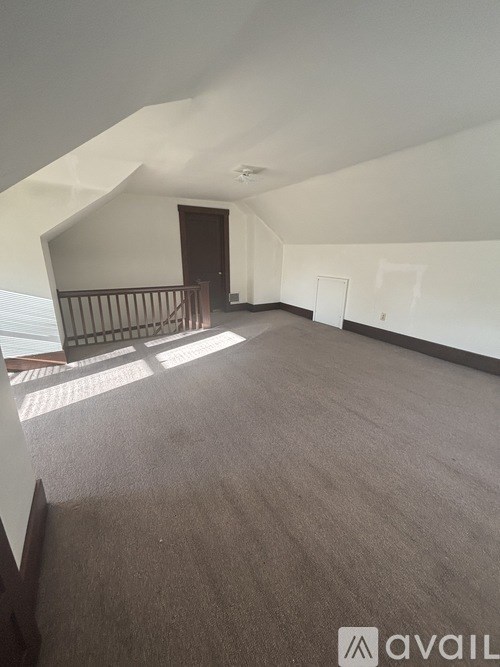 A spacious room with a carpeted floor and a balcony with a railing.
