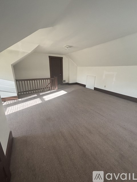 A spacious room with a carpeted floor and a balcony with a railing.