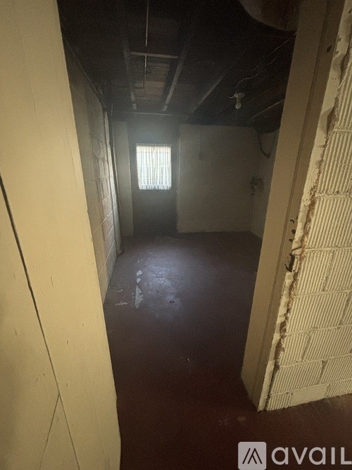 A long hallway with a window and a door at the end.